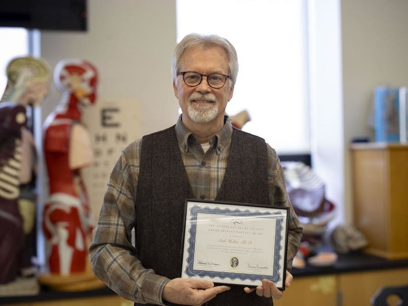 Professor Dale Holen shows off his award certificate that he recently received from the Northeast Algal Society