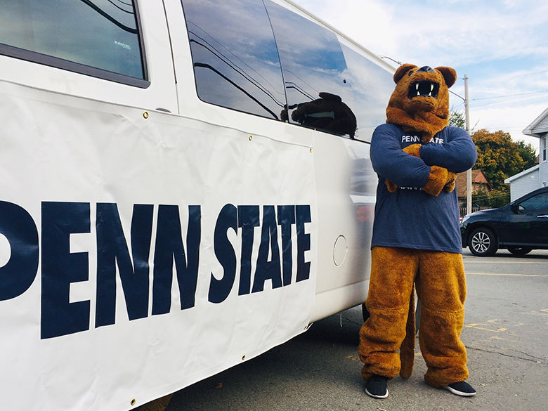 Lion mascot stands by vehicle marked Penn State