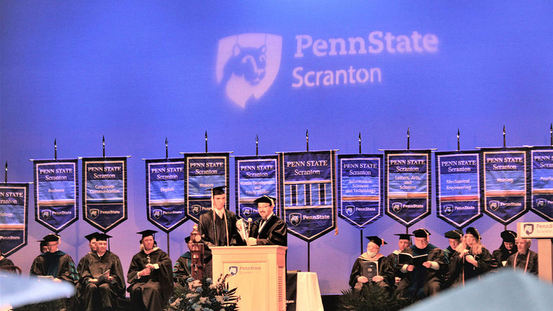 man at podium presents graduate with a medal