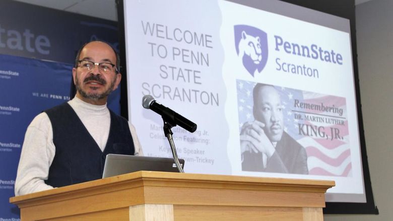 Chancellor Marwan Wafa speaking at podium with MLK Jr image on screen behind him