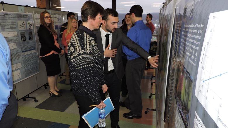 Student explaining their poster at the Undergraduate Research and Scholarship Fair