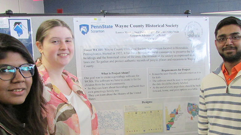 Students at past research fair displaying their research poster