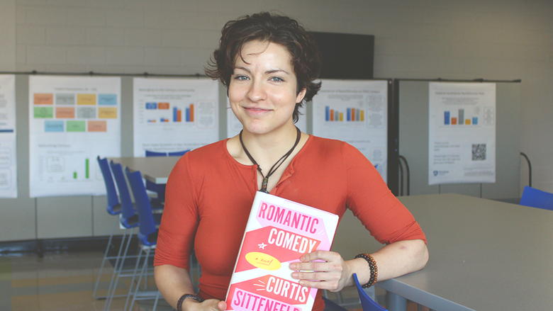 Student Jade Snyder smiling and posing with her chosen book "Romantic Comedy".
