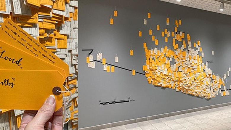 Exhibit of memorial wall of toe tags for Hostile Terrain project