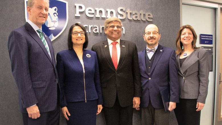 group of PSU officials and special guests posing for a photo in front of Penn State wall
