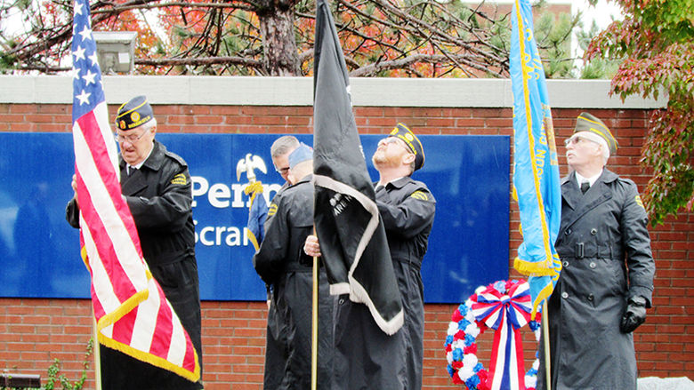 four veterans in uniform raise flags at Penn State Scranton in ceremony