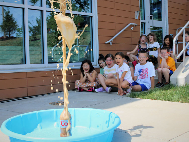 Campers from last summer's science camp watch a bottle volcano erupting